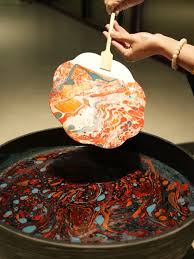 A marbled lacquer fan in flowing reds and golds